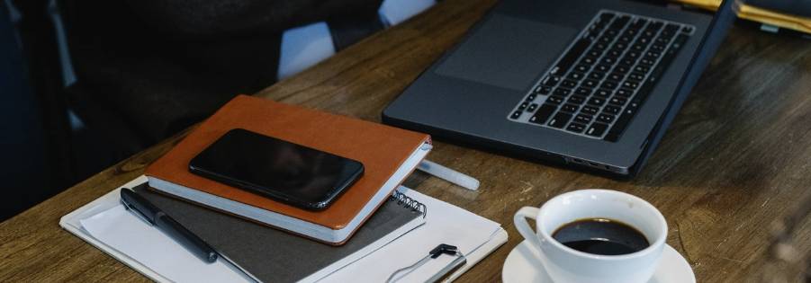 Laptop on a table with some books and a cup of coffee