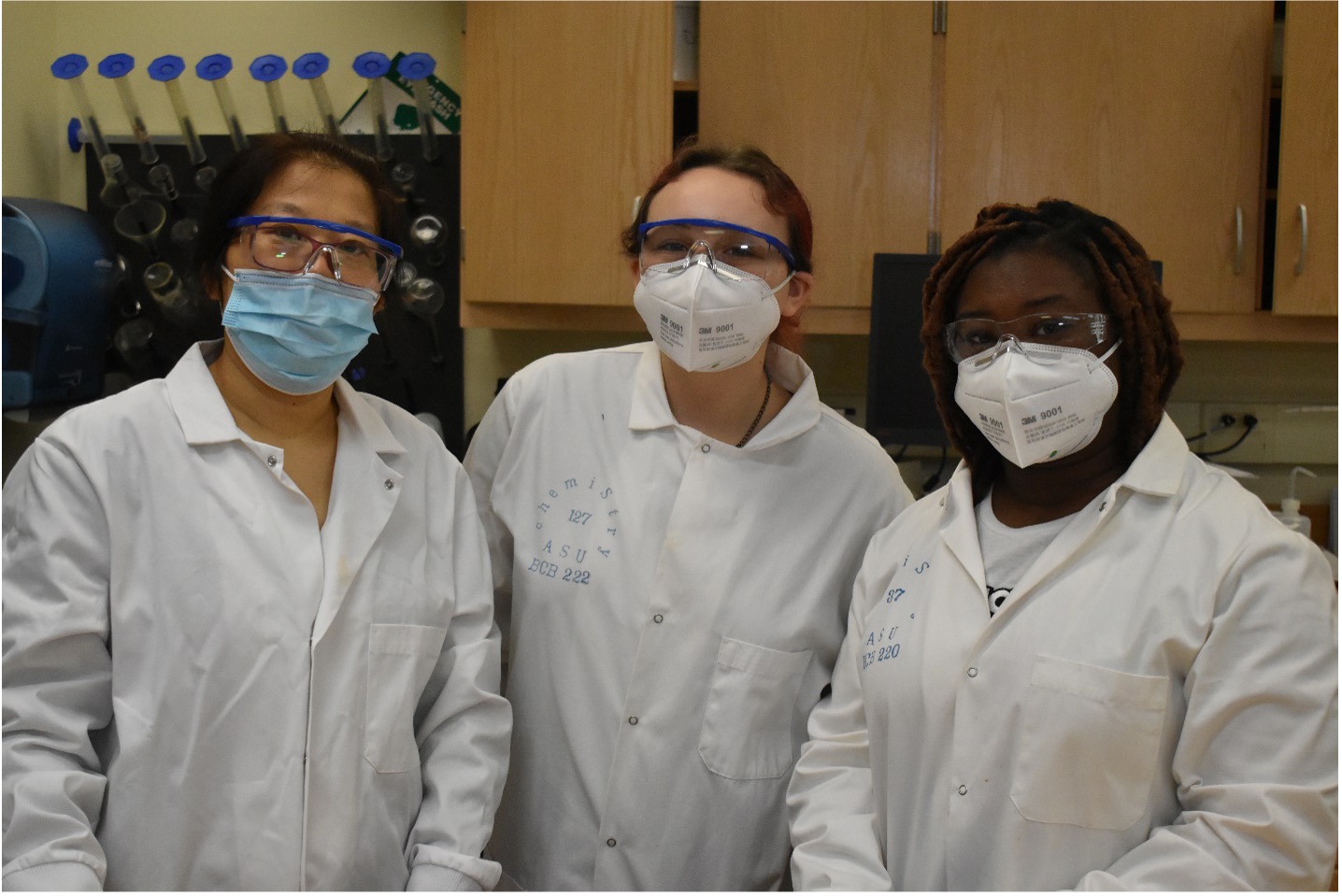 Student and faculty in lab coats smiling